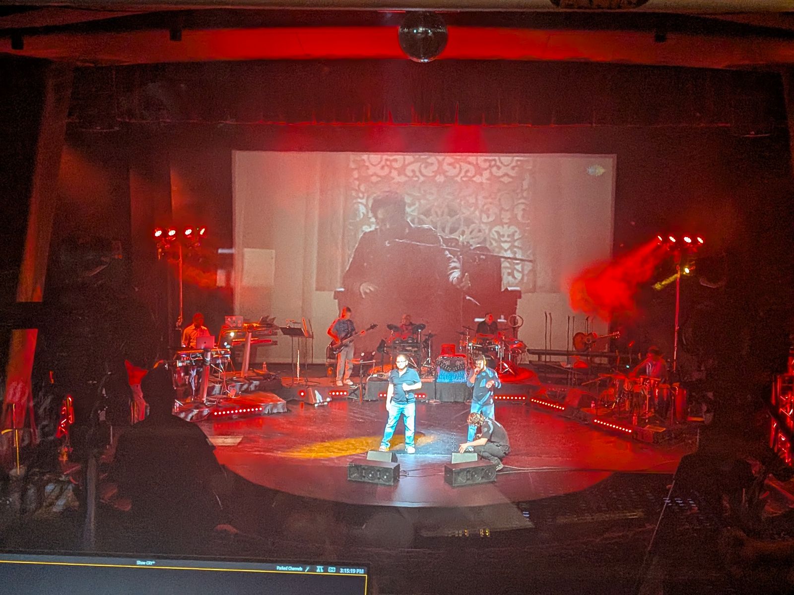 Live band in red light with IMAG projection, console in the foreground